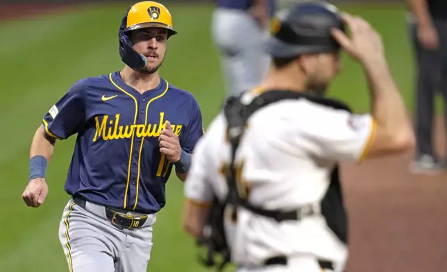 Milwaukee Brewers' Sal Frelick, left, scores the second of two runs driven in on a single by Joey Ortiz, as Pittsburgh Pirates catcher Joey Bart looks away during the second inning of a baseball game in Pittsburgh, Tuesday, Sept. 24, 2024. (AP Photo/Gene J. Puskar)