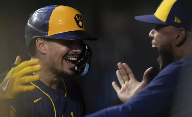 Milwaukee Brewers' Willy Adames, left, celebrates in the dugout after hitting a three-run home run during the third inning of a baseball game against the Cincinnati Reds, Saturday, Aug. 31, 2024, in Cincinnati. (AP Photo/Carolyn Kaster)