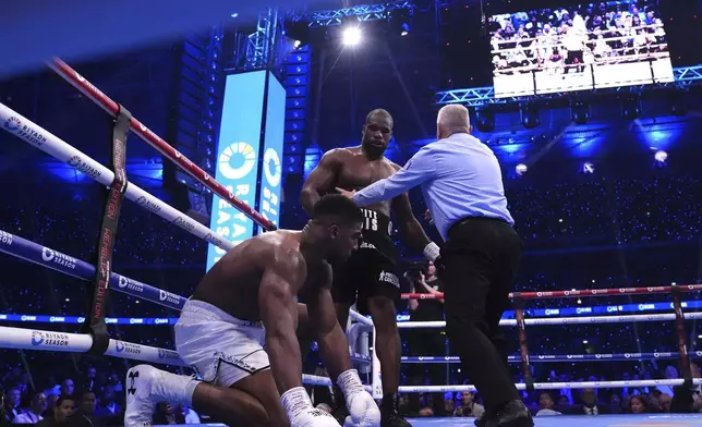 Daniel Dubois, centre, knocks down Anthony Joshua in the IBF World Heavyweight bout at Wembley Stadium, in London, Saturday, Sept. 21, 2024. (Bradley Collyer/PA via AP)