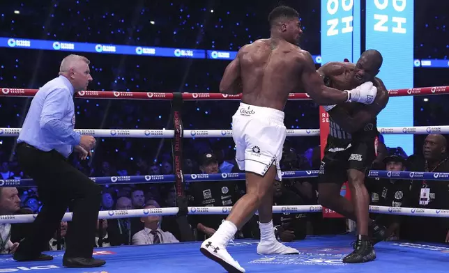 Anthony Joshua, centre, and Daniel Dubois, right, fight in the IBF World Heavyweight bout at Wembley Stadium, in London, Saturday, Sept. 21, 2024. (Bradley Collyer/PA via AP)