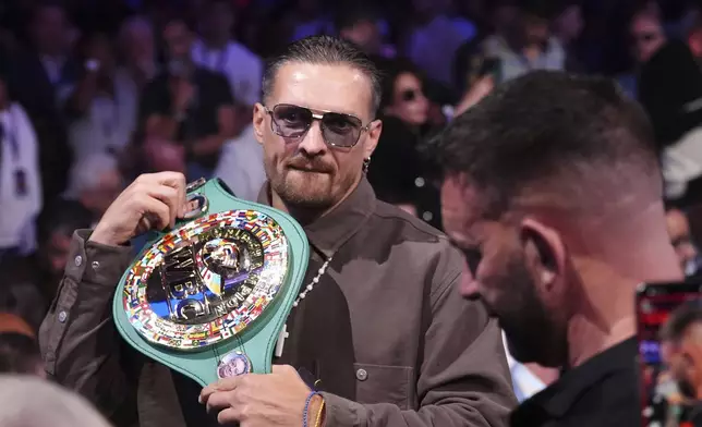 Ukrainian boxer Oleksandr Usyk in the stands with his belt at Wembley Stadium, in London, Saturday, Sept. 21, 2024. (Bradley Collyer/PA via AP)