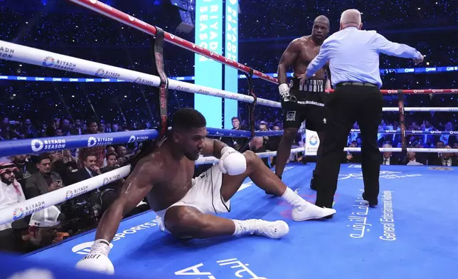 Anthony Joshua, left, knocked down by Daniel Dubois in the IBF World Heavyweight bout at Wembley Stadium, in London, Saturday, Sept. 21, 2024. (Bradley Collyer/PA via AP)