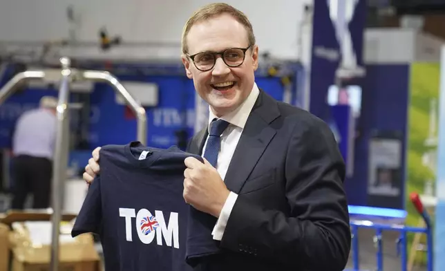 Former Security Minister Tom Tugendhat holds up one of his T-shirts during the Conservative Party Conference at International Convention Centre in Birmingham, England, Sunday, Sept. 29, 2024. (Stefan Rousseau/PA via AP)