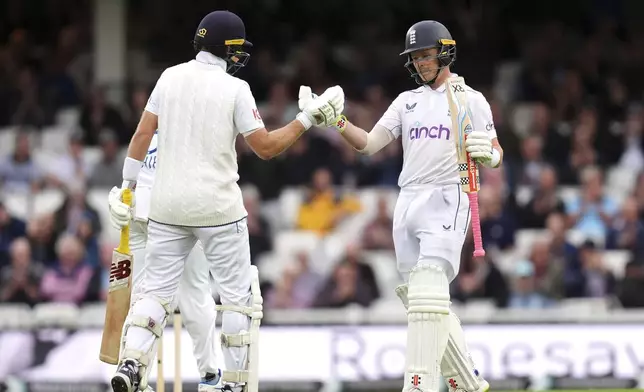 England's Ollie Pope, right, celebrates his half-century with teammate Joe Root during day one of the Third Men's Test between England and Sri Lanka at The Oval, London, Friday Sept. 6, 2024. (John Walton/PA via AP)