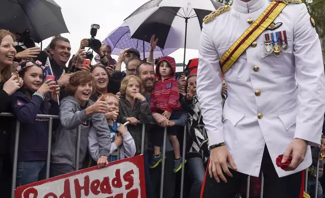 FILE - Britain's Prince Harry, right, as he reacts after shaking hands with kids holding up a sign during a visit to the Australian War Memorial in Canberra, Australia, Monday, April 6, 2015. (AP Photo/Lukas Coch, Pool, File)