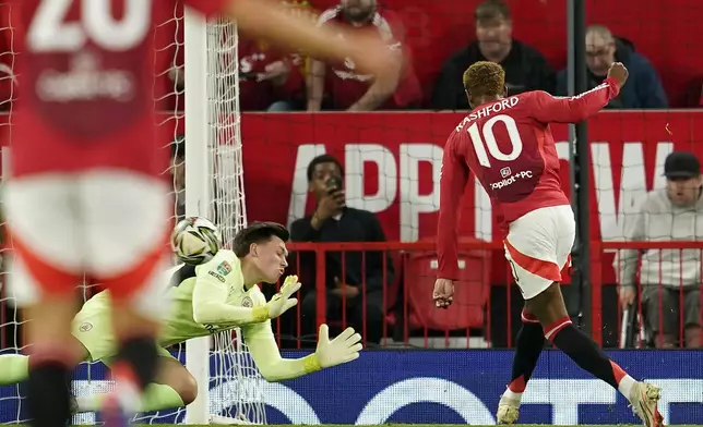 Manchester United's Marcus Rashford scores the opening goal against Barnsley's goalkeeper Gabriel Slonina during the English League Cup soccer match between Manchester United and Barnsley at Old Trafford, Manchester, England, Tuesday, Sept. 17, 2024. (AP Photo/Dave Thompson)