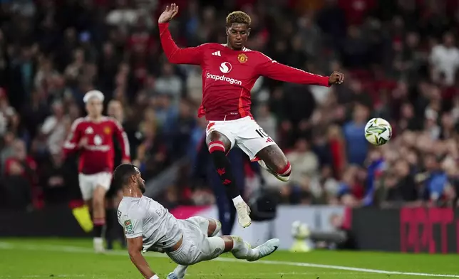 Manchester United's Marcus Rashford, top, is tackled by Barnsley's Barry Cotter during the English League Cup soccer match between Manchester United and Barnsley at Old Trafford, Manchester, England, Tuesday, Sept. 17, 2024. (Mike Egerton/PA via AP)