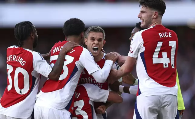 Arsenal's Leandro Trossard, centre, celebrates with teammates after scoring his side's third goal during the English Premier League soccer match between Arsenal and Leicester City at the Emirates Stadium in London, Saturday, Sept. 28, 2024. (AP Photo/Ian Walton)
