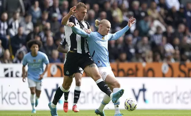 Newcastle United's Dan Burn, left, and Manchester City's Erling Haaland battle for the ball during the Premier League match between Newcastle and Manchester City, at St James' Park, Newcastle upon Tyne, England, Saturday Sept. 28, 2024. (Owen Humphreys/PA via AP)