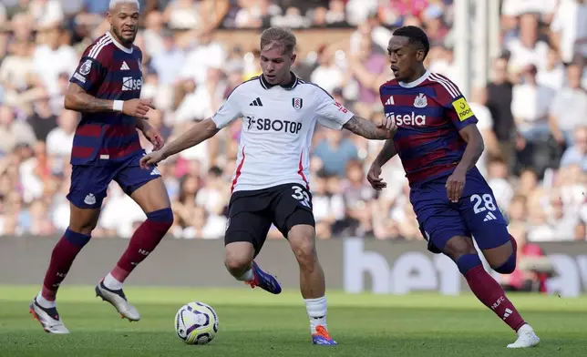 Fulham's Emile Smith Rowe and Newcastle United's Joe Willock, right, battle for the ball during the English Premier League soccer match between Fulham and Newcastle United at Craven Cottage, London, Saturday Sept. 21, 2024. (Jonathan Brady/PA via AP)