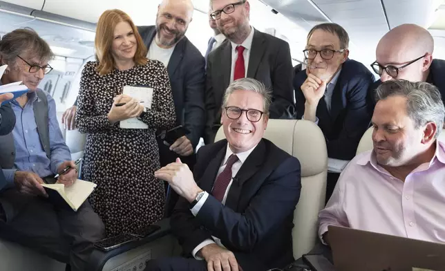 Britain's Prime Minister Keir Starmer, center, talks to the media on board his plane as he flies to Washington DC., Thursday Sept. 12, 2024. (Stefan Rousseau/Pool via AP)