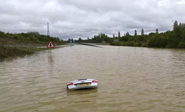 A view of an open boot of a car visible, submerged in flood water after heavy rainfall, on the A421 in Marston Moretaine, Bedfordshire, England, Monday, Sept. 23, 2024, as parts of Britain have been struck by flash floods. (Joe Giddens/PA via AP)