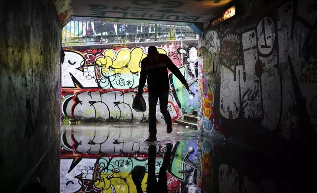 A person shelters from the rain in a flooded underpass by Lawrence Hill Roundabout, Bristol, England, Monday Sept. 23, 2024. (Ben Birchall/PA via AP)