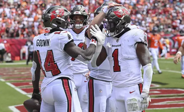 Tampa Bay Buccaneers wide receiver Chris Godwin, left, celebrates his touchdown catch against the Denver Broncos with teammates including running back Rachaad White (1) during the first half of an NFL football game, in Tampa, Fla. on Sunday, Sept. 22, 2024. (AP Photo/Jason Behnken)