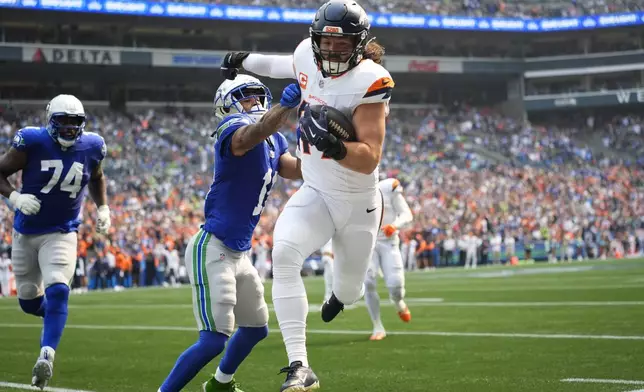 Denver Broncos linebacker Alex Singleton (49) runs an interception thrown by Seattle Seahawks quarterback Geno Smith as Seattle Seahawks wide receiver Jaxon Smith-Njigba (11) defends during the first half of an NFL football game Sunday, Sept. 8, 2024, in Seattle. (AP Photo/Lindsey Wasson)