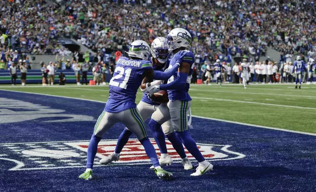 Seattle Seahawks cornerback Devon Witherspoon (21) and safety Julian Love, right, and safety Rayshawn Jenkins, center, react after an interception near the goal line during the first half of an NFL football game against the Denver Broncos, Sunday, Sept. 8, 2024, in Seattle. (AP Photo/John Froschauer)