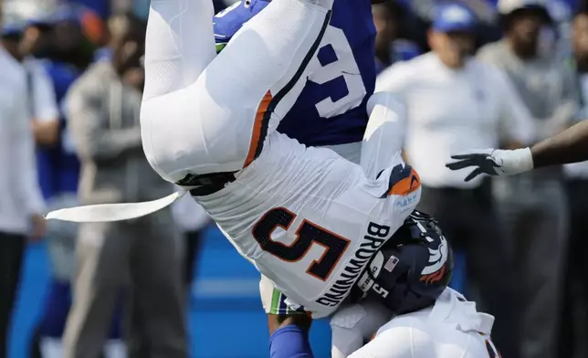 Seattle Seahawks running back Kenneth Walker III (9) carries the ball as Denver Broncos linebacker Baron Browning (5) defends during the first half of an NFL football game Sunday, Sept. 8, 2024, in Seattle. (AP Photo/John Froschauer)