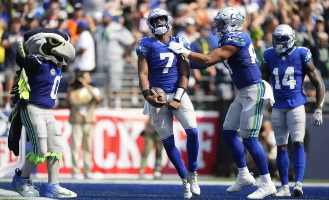 Seattle Seahawks quarterback Geno Smith (7) celebrates after scoring a touchdown with teammates tight end Noah Fant, second from right, and wide receiver DK Metcalf (14) during the first half of an NFL football game Sunday, Sept. 8, 2024, in Seattle. (AP Photo/Lindsey Wasson)