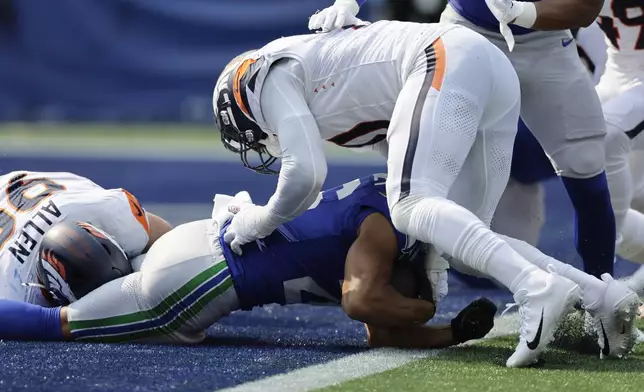 Denver Broncos defensive end Zach Allen, left, stops Seattle Seahawks running back Zach Charbonnet (26) for a safety as Denver Broncos linebacker Jonathon Cooper, top defends during the first half of an NFL football game Sunday, Sept. 8, 2024, in Seattle. (AP Photo/John Froschauer)