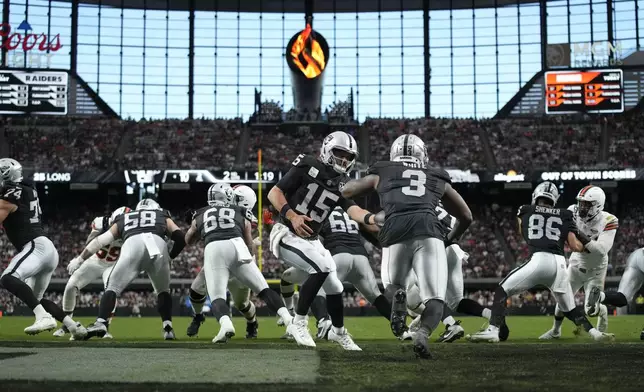 Las Vegas Raiders quarterback Gardner Minshew hands off to running back Zamir White during the first half of an NFL football game against the Cleveland Browns Sunday, Sept. 29, 2024, in Las Vegas. (AP Photo/John Locher)