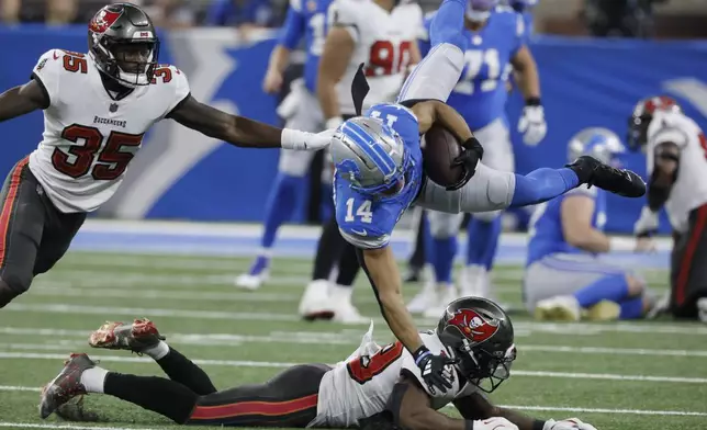 Detroit Lions wide receiver Amon-Ra St. Brown (14) is upended by Tampa Bay Buccaneers safety Tykee Smith (23) during the first half of an NFL football game, Sunday, Sept. 15, 2024, in Detroit. (AP Photo/Duane Burleson)