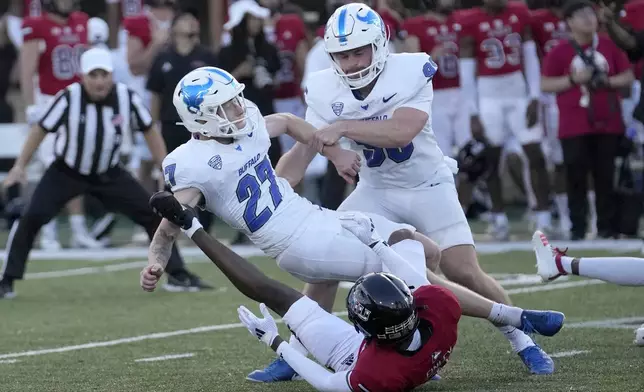 Buffalo place kicker Upton Bellenfant falls over a Northern Illinois defender after kicking the game winning field goal off the hold of Ethan Duane, during the team's 23-20 upset overtime win in an NCAA college football game Saturday, Sept. 21, 2024, in DeKalb, Ill. (AP Photo/Charles Rex Arbogast)