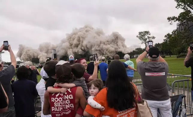 Tuff Gary, left, and Morgan LeBlanc with their children Hudson, Tuff, Jr., and Zander, of Jenning, La., watch the implosion of the Hertz Tower, that was heavily damaged after Hurricanes Laura and Delta in 2020, in Lake Charles, La., Saturday, Sept. 7, 2024. (AP Photo/Gerald Herbert)