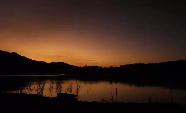 CORRECTS THE CITY - The sun sets over Serra da Mesa lake as nearby fires spread through the environmental protection area of Pouso Alto, in Chapada dos Veadeiros National Park, during dry season, in Colinas do Sul, Goias state, Brazil, Monday, Sept. 9, 2024. (AP Photo/Eraldo Peres)