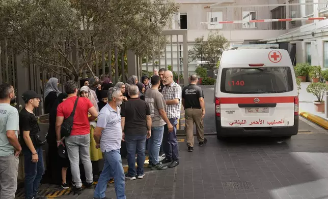 CORRECTS DAY TO TUESDAY WHEN INJURED Lebanese Red Cross ambulance passes next of the families of victims who were injured on Tuesday by their exploding handheld pagers, at the emergency entrance of the American University hospital, in Beirut, Lebanon, Wednesday, Sept. 18, 2024. (AP Photo/Hussein Malla)