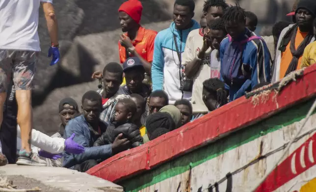 CORRECTS TO DELETE THE EXTRANEOUS WORD OF "UNAUTHORIZED" - FILE - A child is carried ashore from a crowded wooden boat as migrants arrive at the port in La Restinga on the Canary island of El Hierro, Spain, on Aug. 18, 2024. (AP Photo/Maria Ximena, File)