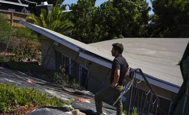 A reporter stands near a home that collapsed due to ongoing landslides in Rancho Palos Verdes, Calif., Tuesday, Sept. 3, 2024. (AP Photo/Jae C. Hong)