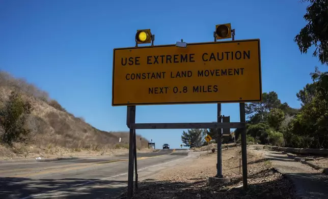 A warning sign stands along a section of road affected by ongoing landslides in Rancho Palos Verdes, Calif., Tuesday, Sept. 3, 2024. (AP Photo/Jae C. Hong)