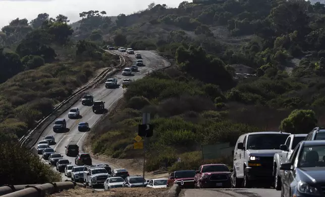 Motorists drive along a section of the road affected by ongoing landslides in Rancho Palos Verdes, Calif., Tuesday, Sept. 3, 2024. (AP Photo/Jae C. Hong)