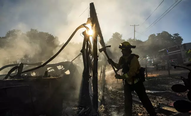 Firefighter Jonathan Lievanos extinguishes hot spots at a home destroyed by the Boyles fire in Clearlake, Calif., on Sunday, Sept. 8, 2024. (AP Photo/Noah Berger)