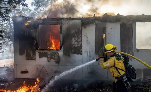 Firefighter Gus Laws extinguishes flames on a home as the Boyles fire burns in Clearlake, Calif., on Sunday, Sept. 8, 2024. (AP Photo/Noah Berger)