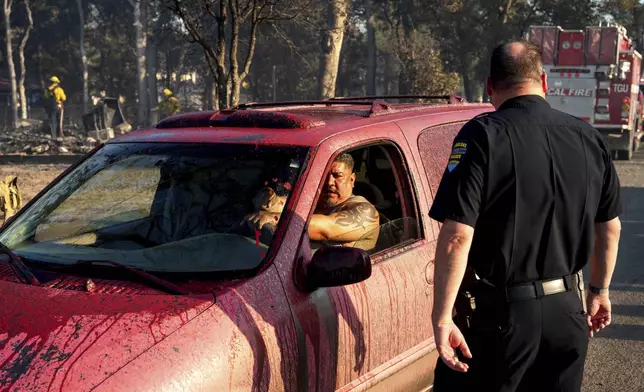 Fire retardant coats Joel Ayon's car as he drives through a neighborhood impacted by the Boyles fire in Clearlake, Calif., on Sunday, Sept. 8, 2024. (AP Photo/Noah Berger)