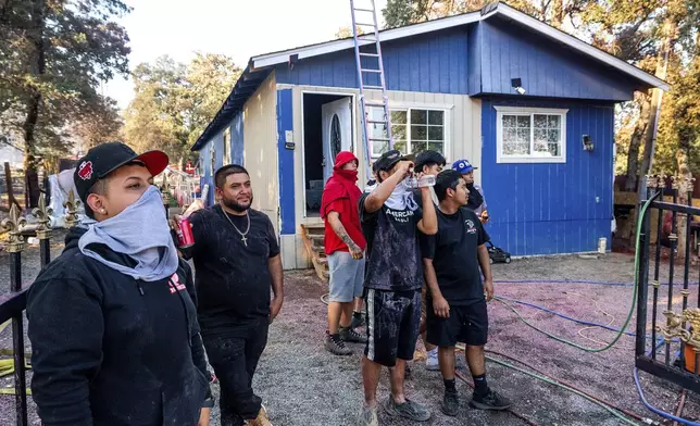 Residents watch as firefighters mop up at a home destroyed by the Boyles fire in Clearlake, Calif., on Sunday, Sept. 8, 2024. (AP Photo/Noah Berger)