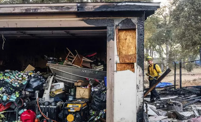 Firefighter Nolan Graham works to extinguish a smoldering garage as the Boyles fire burns in Clearlake, Calif., on Sunday, Sept. 8, 2024. (AP Photo/Noah Berger)