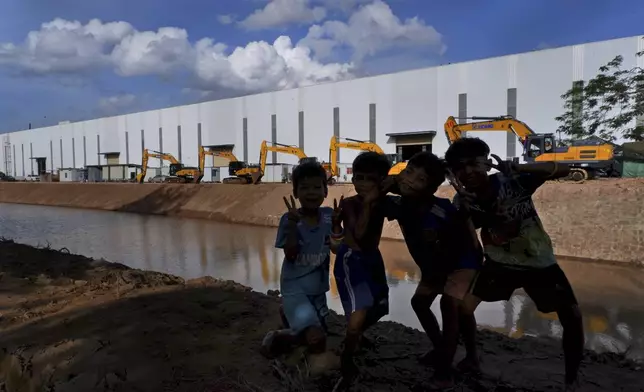 Children pose in front of bulldozers lined along the Funan Techo canal at Prek Takeo village, eastern Phnom Penh, Cambodia, Tuesday, July 30, 2024. (AP Photo/Aniruddha Ghosal)