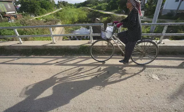 A villager who lives along the Funan Techo Canal rides a bicycle past a bridge at Prek Takeo village, eastern Phnom Penh Cambodia, Tuesday, July 30, 2024. (AP Photo/Heng Sinith)