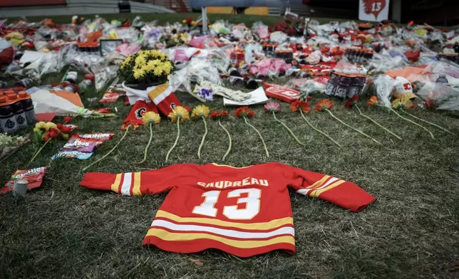 Flowers and memorabilia for former Calgary Flames player Johnny Gaudreau and his brother Matthew lie on the grass outside the Saddledome in Calgary, Alberta, Wednesday, Sept. 4, 2024. (Jeff McIntosh/The Canadian Press via AP)