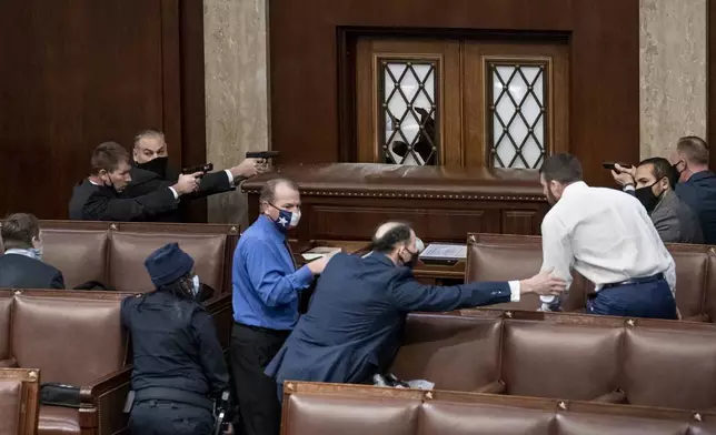 FILE - Security forces draw their guns as rioters loyal to President Donald Trump try to break into the House of Representatives chamber to disrupt the Electoral College process, at the Capitol in Washington, Jan. 6, 2021. (AP Photo/J. Scott Applewhite, File)