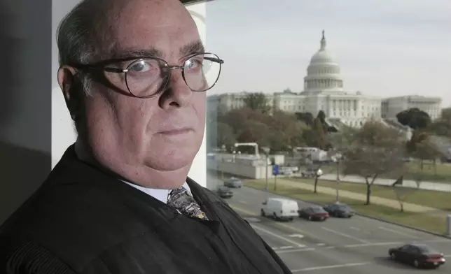 FILE - U.S. District Court Judge Royce Lamberth is pictured in his courthouse office, Nov. 23, 2005, in Washington, with the U.S. Capitol standing behind. Inside Washington’s federal courthouse, there's no denying the reality of Jan. 6, 2021. Day after day, judges and jurors silently absorb chilling sights and sounds from television screens — of rioters beating police, shattering windows and hunting for lawmakers. Hundreds of cases have systematically documented the weapons wielded, crimes committed, lives altered by physical and emotional damage. (AP Photo/Charles Dharapak, File)