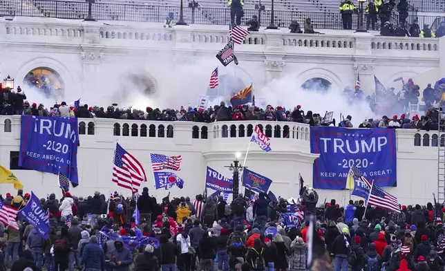 FILE - Rioters at the U.S. Capitol on Jan. 6, 2021, in Washington. Michael Foy, who traveled to Washington alone from his Michigan home on the morning of Jan. 6, wildly swung a hockey stick at officers at least 11 times in 16 seconds, while other rioters attacked police with a crutch, flagpoles, and other makeshift weapons during an explosion of violence at mouth of the Lower West Terrace Tunnel. Earlier, he picked up a sharpened metal pole and hurled it like a spear at police. (AP Photo/John Minchillo, File)