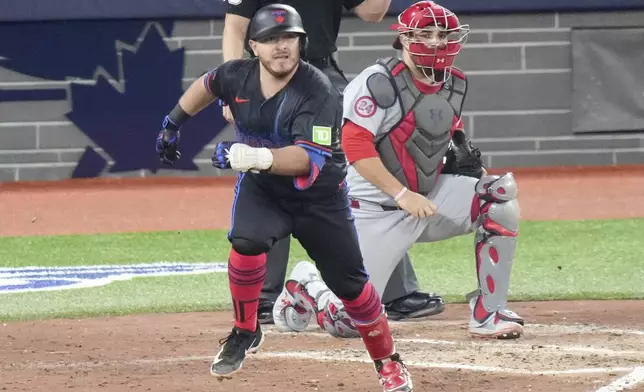 Toronto Blue Jays' Alejandro Kirk, front left, runs for first base after hitting an RBI single in front of St. Louis Cardinals catcher Pedro Pagés, right, during fourth-inning baseball game action in Toronto, Friday, Sept. 13, 2024. (Chris Young/The Canadian Press via AP)