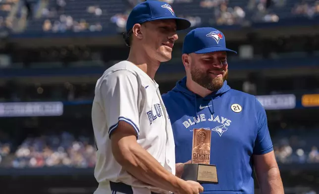 Toronto Blue Jays' Chris Bassitt, left, is given the Roberto Clemente Award by manager John Schneider, right, ahead of a baseball game against the St. Louis Cardinals in Toronto, Sunday, Sept. 15, 2024. (Paige Taylor White/The Canadian Press via AP)