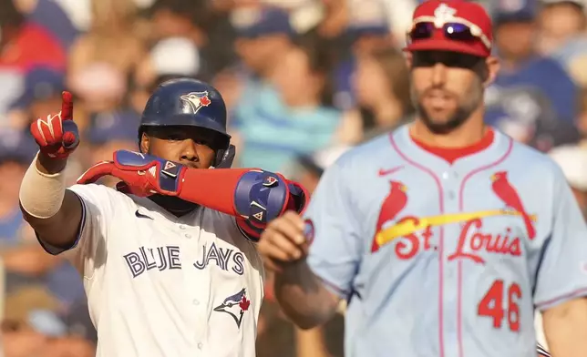 Toronto Blue Jays' Vladimir Guerrero Jr. gestures to the bench as he stands alongside St. Louis Cardinals first baseman Paul Goldschmidt after hitting an RBI single during seventh inning interleague MLB baseball action in Toronto, Saturday, September 14, 2024. (Chris Young/The Canadian Press via AP)