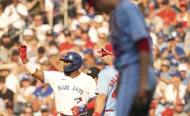 Toronto Blue Jays' Vladimir Guerrero Jr. gestures for the ball after hitting an RBI single, his 500th RBI as a Blue Jay, as he stands with St. Louis Cardinals first baseman Paul Goldschmidt during seventh inning interleague MLB baseball action in Toronto, Saturday, September 14, 2024. (Chris Young/The Canadian Press via AP)