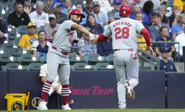 St. Louis Cardinals' José Fermín, left, high-fives Nolan Arenado (28) after Arenado scored on a bases-loaded walk in the first inning of a baseball game against the Milwaukee Brewers, Wednesday, Sept. 4, 2024, in Milwaukee. (AP Photo/Kayla Wolf)