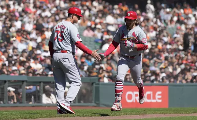 St. Louis Cardinals' Brendan Donovan, right, is congratulated by third base coach Ron Warner (75) as he rounds the bases after hitting a solo home during the third inning of a baseball game against the San Francisco Giats, Sunday, Sept. 29, 2024, in San Francisco. (AP Photo/Tony Avelar)